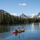 Couple in tandem kayak floating through beautiful mountain scenery